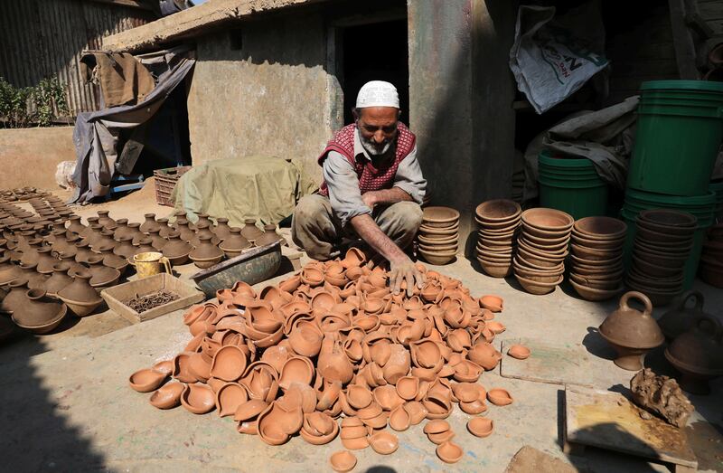 A Kashmiri potter arranges earthen lamps after he takes it out from an oven at his home on the outskirts of Srinagar. EPA