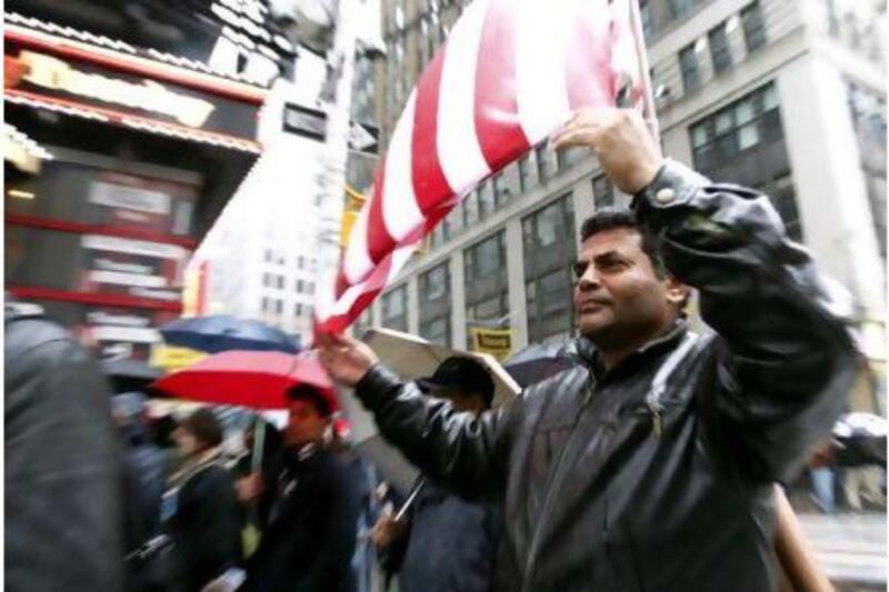A man uses an American flag to shelter himself from the rain during the 'Today, I Am A Muslim, Too' rally in New York City on Sunday, held to protest at the targeting of American Muslims and Arabs.