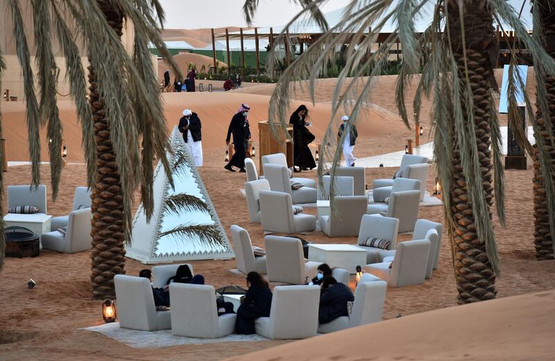 Visitors relax in a lounge area beneath palm trees at the "Riyadh Oasis." AFP