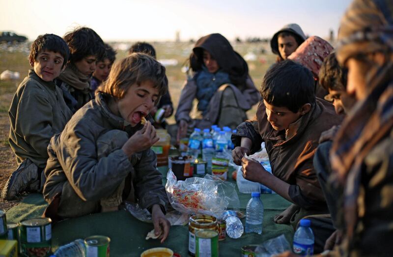 Yazidi boys share a meal in a area held by the US-backed Kurdish-led Syrian Democratic Forces (SDF), in the eastern Syrian province of Deir Ezzor, after fleeing ISIS's embattled holdout of Baghouz.  Eleven Yazidi children were rescued by US-backed forces. AFP