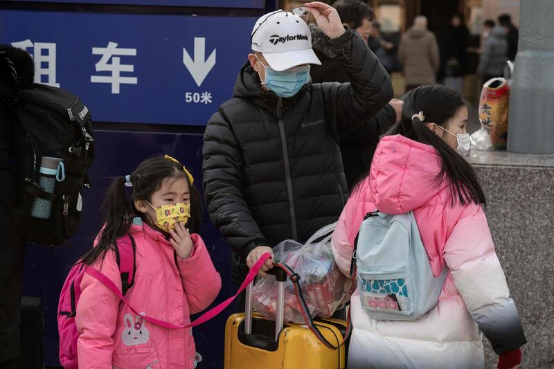 People wearing masks arrive at Beijing railway station to head home for the Lunar New Year.  AFP