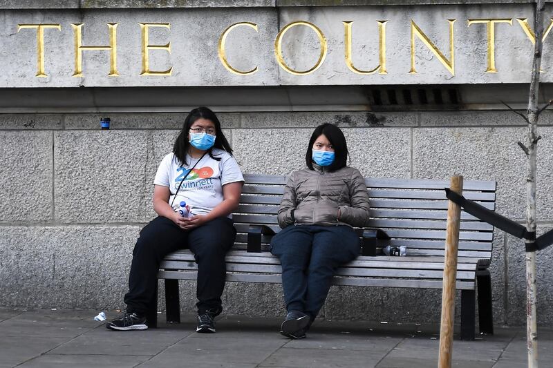 Two women sit on a bench wearing face masks, in London, March 6, 2020. Fearing a possible shortage in protective equipment, health ministers from the European Union are holding an emergency meeting to try to improve their collective response to the novel coronavirus outbreak. Alberto Pezzalli / AP