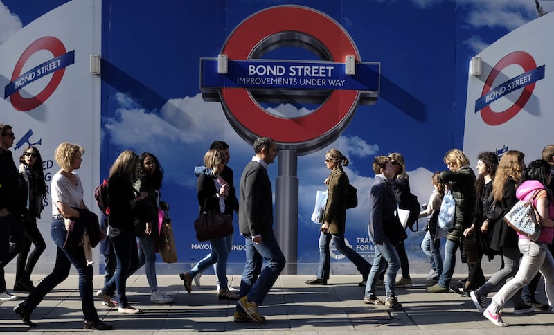 People walk past signs for a London Underground improvement programme during a busy afternoon on Oxford Street in London. Reuters