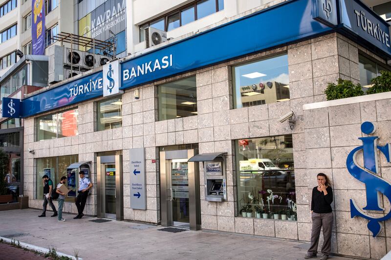 People stand outside a branch of Turkiye Is Bankasi AS, also known as Isbank, in the financial district of Istanbul, Turkey, on Tuesday, Aug. 14, 2018. President Recep Tayyip Erdogan vowed to boycott iPhones in a demonstration of defiance as the U.S. held firm to its demand that Turkey release an evangelical pastor and Turkish executives called for action to bolster the lira. Photographer: Nicole Tung/Bloomberg