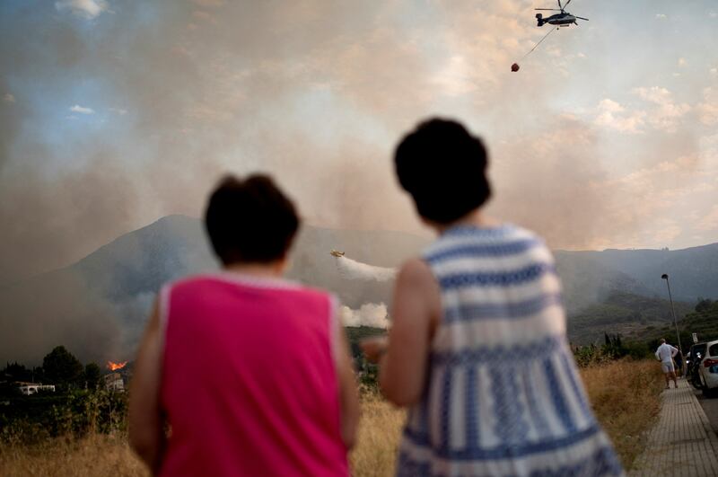 Women watch a plane drop water on to a wildfire near Pego, Spain. Reuters