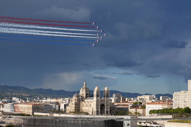 The Patrouille de France aerobatics team leave a tricolour trail of smoke as the Belem, the three-masted sailing ship bringing the Olympic flame from Greece, enters the Old Port in Marseille on Wednesday. AP