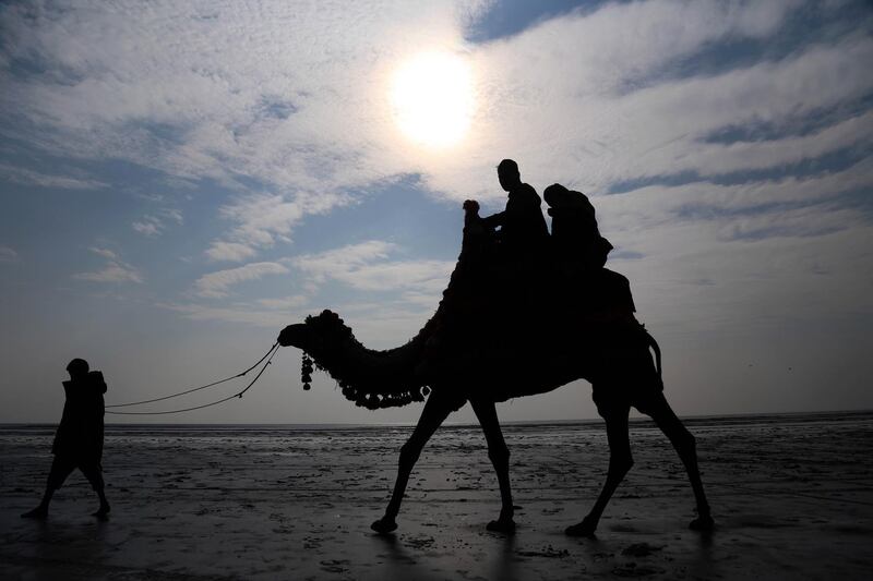 epa08841019 People  ride a camel at a beach in Karachi, Pakistan, 25 November 2020.  EPA/REHAN KHAN