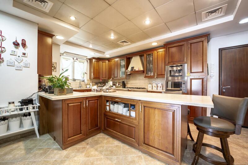 The kitchen comes with wooden cabinets and marble countertops. Courtesy LuxuryProperty.com