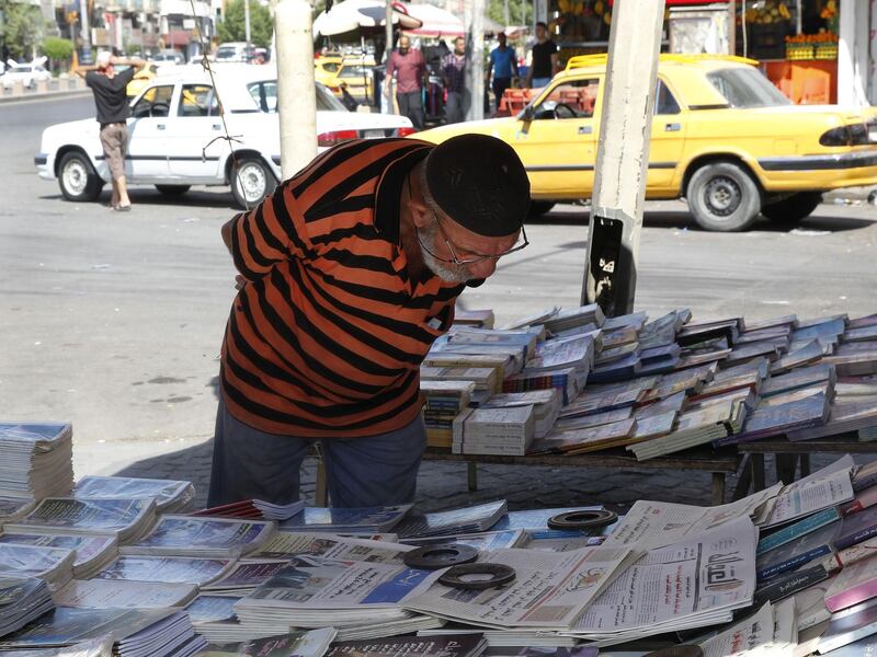 An Iraqi man reads the headlines at a newspaper stand in the capital Baghdad on August 29, 2018. - Iraq's parliament will meet next week for its first session since May elections to choose a speaker and begin the process of forming a government. (Photo by SABAH ARAR / AFP)