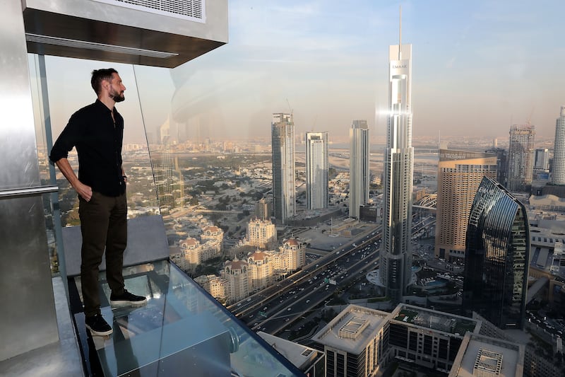 The National's reporter Jamie Goodwin poses inside the glass-bottom slide at Dubai's latest daring attraction, Sky Views Dubai, in Downtown Dubai. Pawan Singh / The National