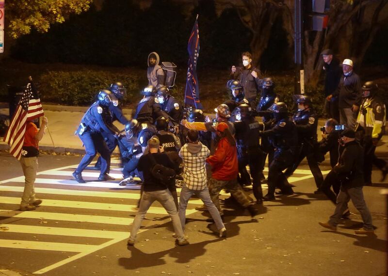 Law enforcement personnel detain a person as supporters of US. Reuters