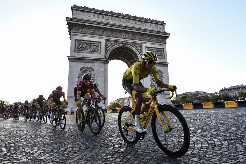 Colombia's Egan Bernal, wearing the overall leader's yellow jersey and cyclists ride down the Champs Elysees avenue next to the Arc de Triomphe on July 28, 2019. AFP