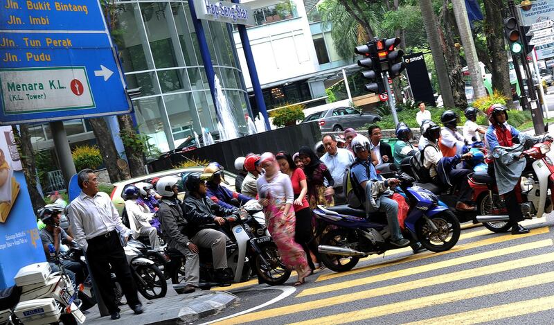Office employees make their way through the busy hour traffic in downtown Kuala Lumpur on July 16, 2010.  The Government announced subsidies for petrol, diesel, liquefied petroleum gas (LPG) and sugar will be reduced as a first step to the gradual subsidy rationalisation programme effective from July 16.  AFP PHOTO / Saeed KHAN / AFP PHOTO / SAEED KHAN