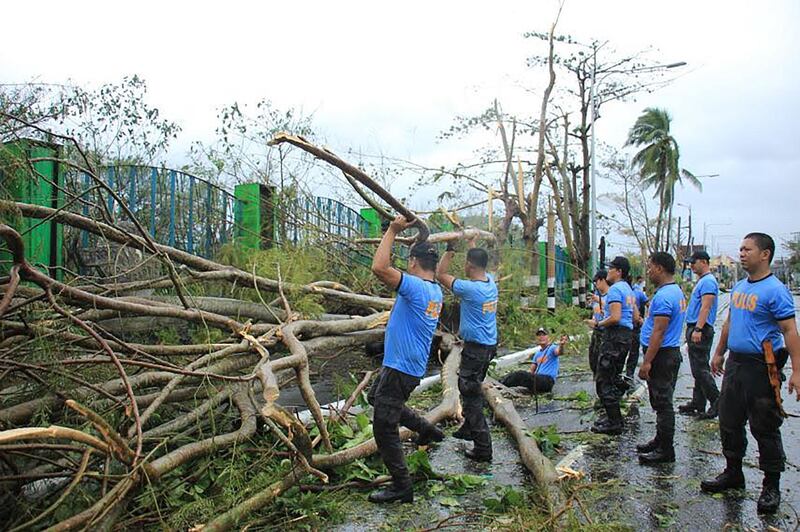 Policemen clear a road with fallen trees near the airport Legaspi City, Albay province, south of Manila after Typhoon Kammuri battered the province. AFP