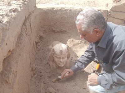 An archaeologist brushes away loose sand after the head of the sphinx had emerged. Photo: Ministry of Tourism & Antiquities