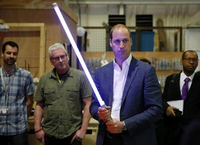 The Duke of Cambridge, Prince William holds a light sabre during a visit to the Star Wars film set on April 19, 2016. Courtesy Adrian Dennis/AFP