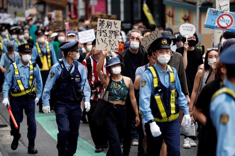 People wearing masks hold placards during a protest march over the alleged police abuse of a Turkish man in Tokyo, Japan.  Reuters