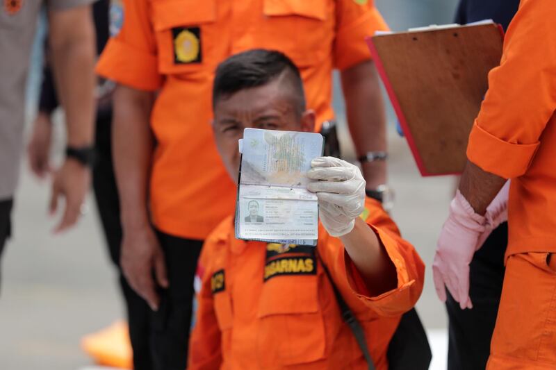 An Indonesian rescuer shows a passport belonging to a passenger from the plane crash, at Tanjung Priok port. EPA