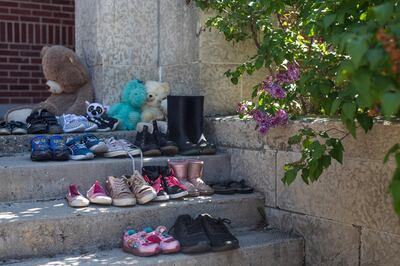 Children's shoes sit on the front steps the former Muskowekwan Indian Residential School during a press conference and prayer vigil at Muscowequan Indian Residential School, one of the last residential schools to close its doors in Canada in 1997 and the last fully intact residential school still standing in Saskatchewan at Muskowekwan First Nation, Saskatchewan, Tuesday, June 1, 2021. The vigil was in response to the remains of 215 children recently found at the Kamloops Indian Residential School. (Kayle Neis/The Canadian Press via AP)