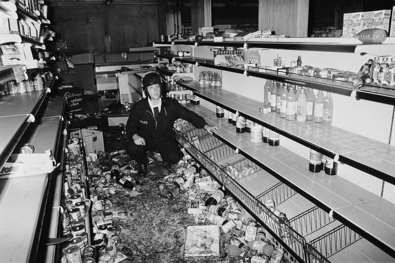 LONDON - OCTOBER 1985: (FILE PHOTO) A police officer in riot gear in a looted grocery shop after the riot on the Broadwater Farm housing estate, Tottenham, London, 6th October 1985. Twenty-Six years later, riots have again broken out in Tottenham on August 6, 2011 following a demonstration protesting the police shooting of twenty-nine-year-old father-of-four Mark Duggan on August 4, 2011 who died in an exchange of gunfire while police were attempting to arrest him.  (Photo by Julian Herbert/Getty Images) *** Local Caption ***  120530701.jpg