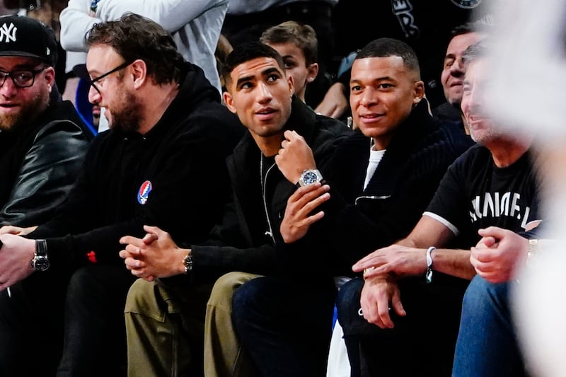 Achraf Hakimi, centre, and Kylian Mbappe watch the NBA game between the Brooklyn Nets and the San Antonio Spurs in New York. AP
