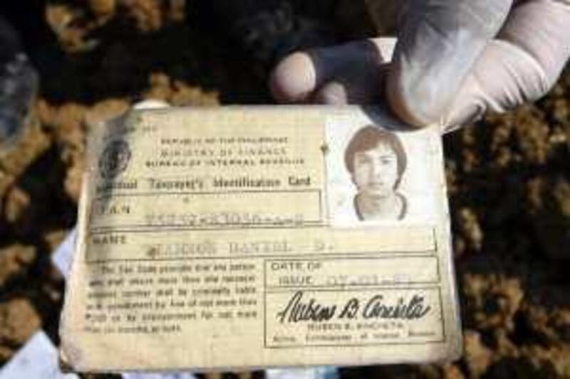 AMPATUAN, PHILIPPINES - DECEMBER 06:  A Filipino forensic expert shows the identification card of massacre victim Daniel Tiamson as they resume digging bodies and evidences at the massacre site on December 6, 2009 in the southern Philippine town of Ampatuan, Maguindanao Province, Philippines. Manila has imposed a military rule in the restive province. The weapons and ammunition are believed to be owned by a Muslim clan linked in late last month's massacre of 64 people, including journalists. On November 23 supporters of local vice-mayor Ismail Mangudadatu and 30 journalists were killed as they prepared to launch his candidacy for the governance of the Maguindanao Province. (Photo by Jeoffrey Maitem/Getty Images) *** Local Caption ***  GYI0059083192.jpg *** Local Caption ***  GYI0059083192.jpg