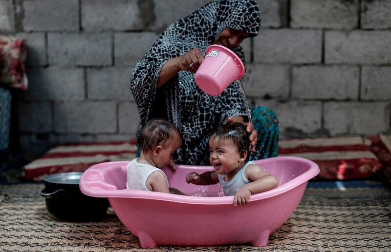 A Palestinian woman gives her children a bath in a slum on the outskirts of the Khan Yunis refugee camp,  southern Gaza Strip, during a heatwave. AFP