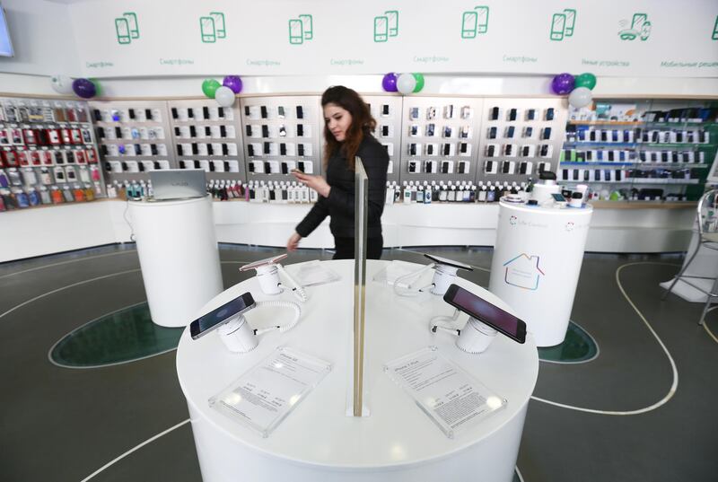 An employee passes a display of Apple Inc. smartphones including iPhone SE, left, and 7 Plus, right, models inside a MegaFon PJSC mobile phone store in Moscow, Russia, on Tuesday, Aug. 29, 2017. MegaFon considers various alternatives for Euroset Holding NV after acquiring VimpelCom Holdings BV���s 50% interest in mobile retailer, the company says in regulatory filing. Photographer: Andrey Rudakov/Bloomberg