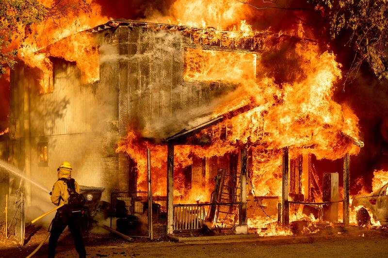 A firefighter sprays water while trying to stop a blaze from spreading to neighbouring homes in Doyle, California. Pushed by heavy winds amid a heatwave, the fire came out of the hills and destroyed several residences.