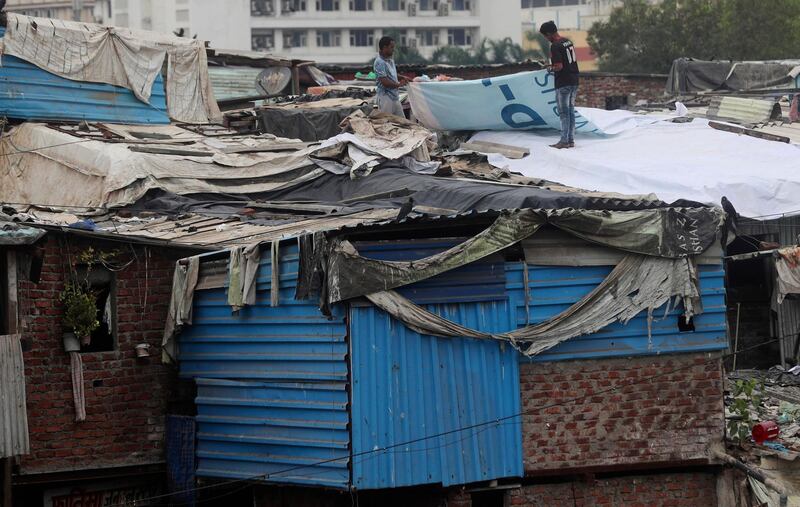People cover the rooftop of a slum house with tarpaulin to protect from rain in Mumbai, India. AP Photo