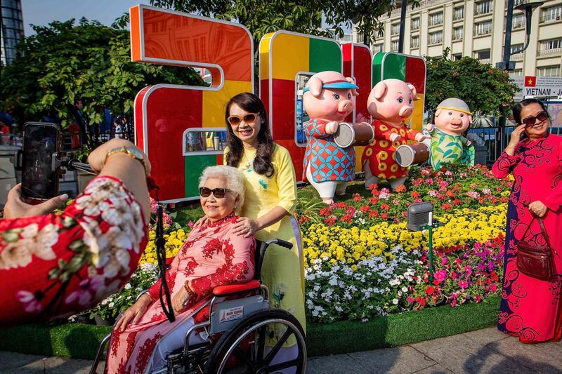 Vietnamese women pose for photographs in front of pig figurines at the Nguyen Hue flower street, decorated for the upcoming Lunar New Year or Tet celebrations in Ho Chi Minh City. AFP