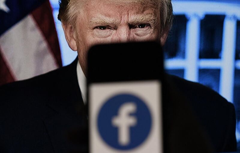 In this photo illustration, a phone screen displays a Facebook logo with the official portrait of former US President Donald Trump on the background, on May 4, 2021, in Arlington, Virginia. Facebook's independent oversight board was set for a momentous decision on the platform's ban of former US president Donald Trump, as debate swirls on the role of social media in curbing hateful and abusive speech while controlling political discourse. - 
 / AFP / Olivier DOULIERY
