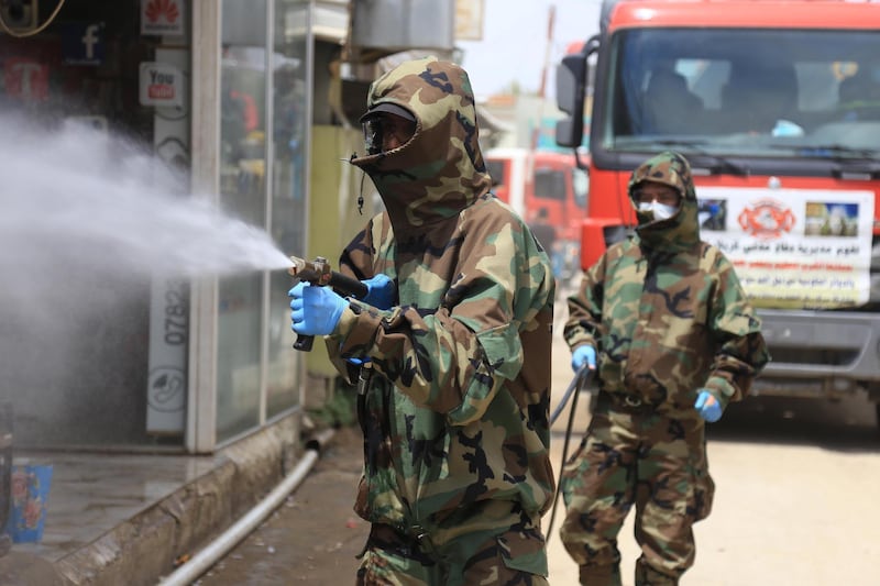 Iraqi civil defence workers sanitise the Tweirij district between Hilla and the southern Iraqi shrine city of Karbala against the spread of the coronavirus pandemic, on April 16, 2020. According to the last toll published this week by Iraq's health ministry there have been so far 1,378 COVID-19 confirmed cases of coronavirus in the country, of which 78 have died. Iraq has imposed a country-wide curfew since March 17, closed schools and shops and banned all international travel as well as movement between the country's provinces. / AFP / Mohammed SAWAF
