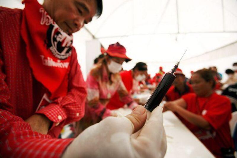 A supporter of the deposed prime minister Thaksin Shinawatra holds a syringe full of blood after making a donation at a protest site in Bangkok yesterday.