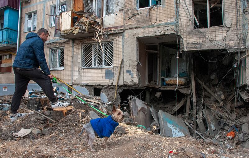 A resident returns with his dog to survey his damaged building in Kharkiv. EPA