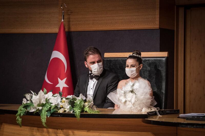 Groom Okan Barut and bride Oya Kulaksiz wear face masks as they take part in their wedding ceremony at the Kadikoy Municipality marriage office in Istanbul, Turkey. Getty Images