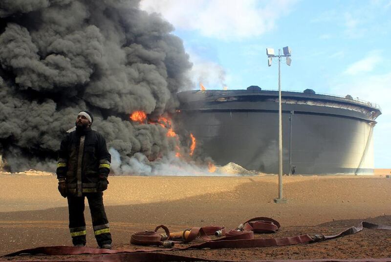 A Libyan fireman stands in front of smoke and flames rising from an oil storage tank at an oil facility in northern Libya's Ras Lanouf region on January 23, 2016. AFP Photo

