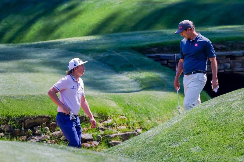 Cam Smith (L) and Adam Scott (R) look for an errant ball in a tributary of Rae's Creek at the thirteenth green during a practice round for the 2021 Masters. EPA