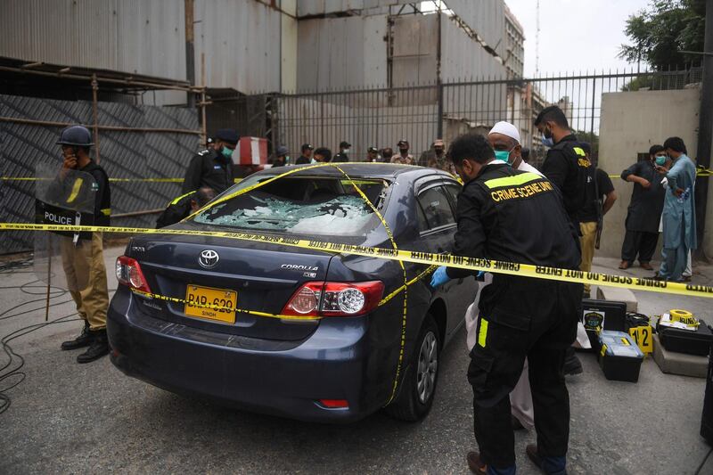 TOPSHOT - Policemen guard as members of Crime Scene Unit investigate around a car used by alleged gunmen at the main entrance of the Pakistan Stock Exchange building in Karachi on June 29, 2020. Gunmen attacked the Pakistan Stock Exchange in Karachi on June 29, with four of the assailants killed, police said. / AFP / Asif HASSAN
