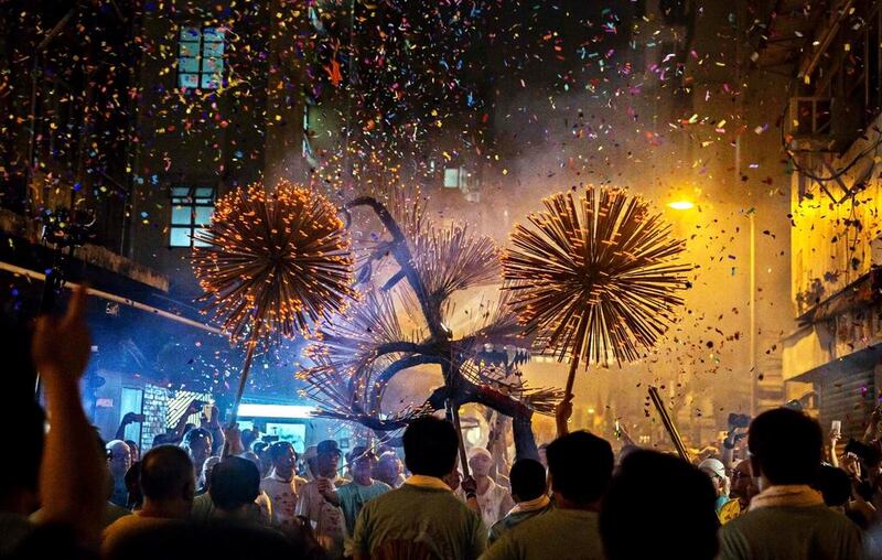 Dance team members hold up the ‘dragon’ as it winds through narrow streets in Hong Kong,  on September 14, 2016, during the Tai Hang fire dragon dance .The century-long tradition involves waving incense-lit, straw-filled dragons to bring blessings to onlookers under the full moon during the annual mid-autumn festival. / AFP / ISAAC LAWRENCE