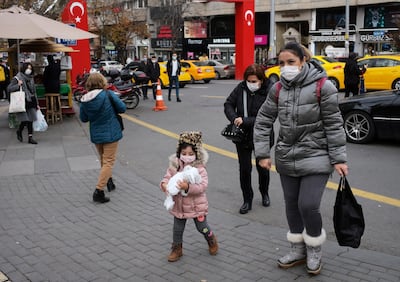 People wearing face masks to protect against coronavirus, walk along a street hours before a two-day weekend curfew, in Ankara, Turkey, Friday, Dec. 18, 2020. Turkey's daily COVID-19 death toll hit a record high on Wednesday, Dec. 16, 2020, with the government announcing close to 30,000 new confirmed infections in the last 24 hours, pushing the total of confirmed cases since the outbreak began in March to nearly 2 million. (AP Photo/Burhan Ozbilici)