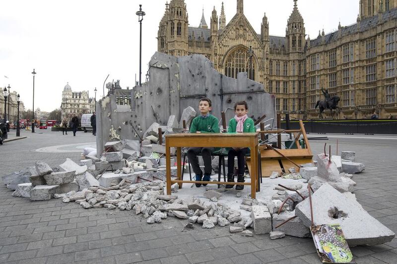 Two children whose school was destroyed in Aleppo pose in a mocked-up bombed classroom, set up at the Houses of Parliament, London, by the charity Save the Children ahead of a donor fundraising conference for Syrian refugees. Justin Tallis / AFP