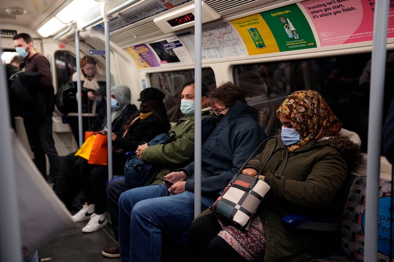 People wear masks on board a London Underground train, where enforcement has been limited. AP