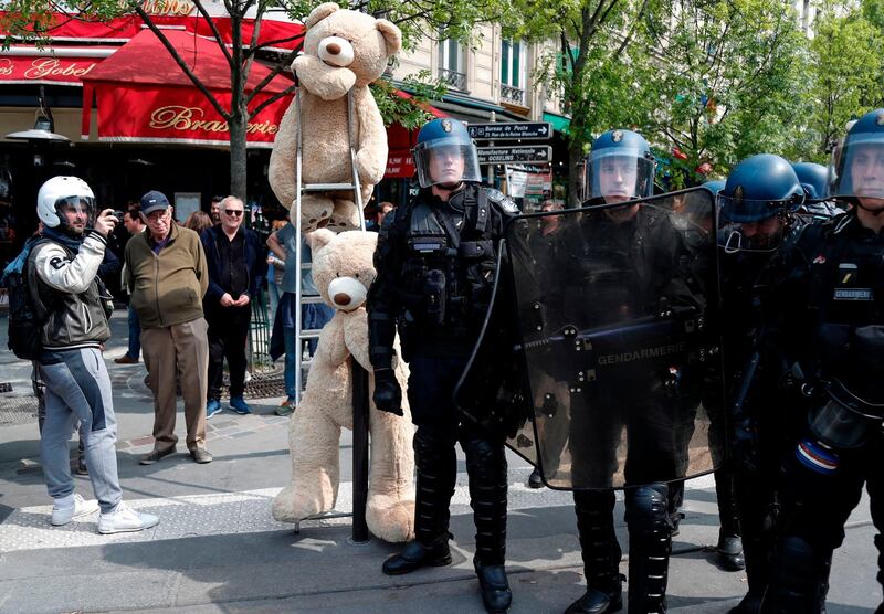 French riot police officers stand next to giant teddy bears, during the May Day demonstration, in Paris. AFP