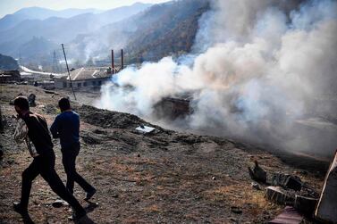 Men look on as a house burns in the village of Charektar outside the town of Kalbajar on November 14, 2020. AFP