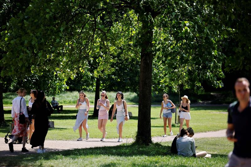 People walk in the sunshine in Hyde Park in London. AFP