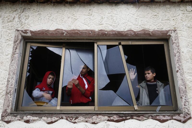Palestinian boys pull shards of glass from a broken window at their home near the site of Israeli overnight attacks in Gaza City. AFP