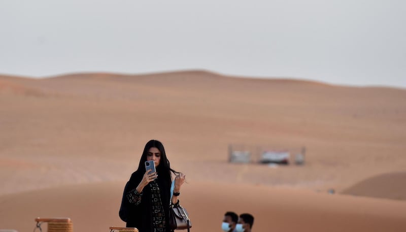 A woman checks her phone at the "Riyadh Oasis." AFP