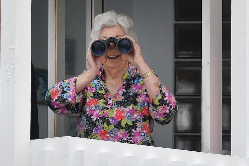 A keen viewer uses binoculars to watch Prince Harry and Meghan as they arrive in Wellington. AFP