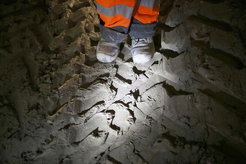 A worker stands on clay dug from a crossrail tunnel marked by machinery tracks and footprints. Peter Macdiarmid / Getty Images